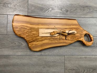 Rustic wooden cutting board with small utensils tied on top.