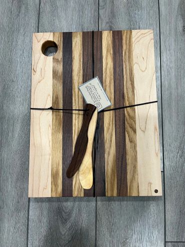 Striped wooden cutting board with two wooden spreaders tied on top.