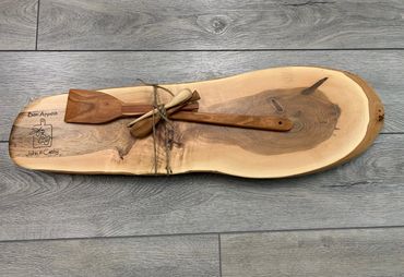 Rustic wooden serving board with kitchen utensils tied in twine.