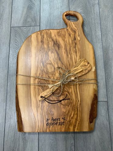 Wooden cutting board with a small spatula tied with twine, engraved 'bon appétit'.