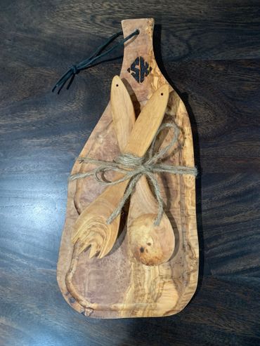 Wooden salad servers tied with a rustic string on a wooden cutting board.