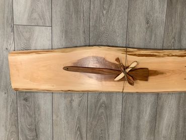 Handcrafted wooden cutting board with a wooden spreader tied on top.