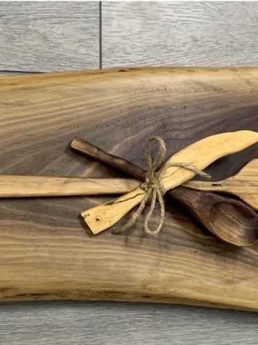 Handcrafted wooden kitchen tools tied together on a rustic wooden board.