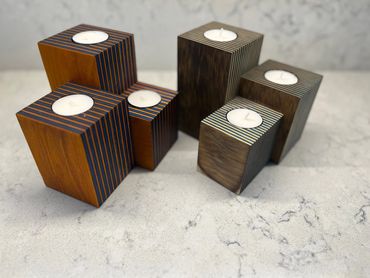 Two sets of wooden candle holders with striped designs on a marble surface.