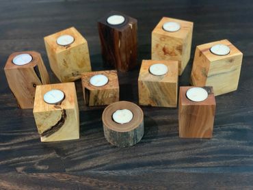 Wooden candle holders with tealight candles on a dark wooden surface.