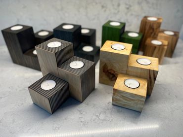 Wooden candle holders in various shapes and finishes on a marble surface.