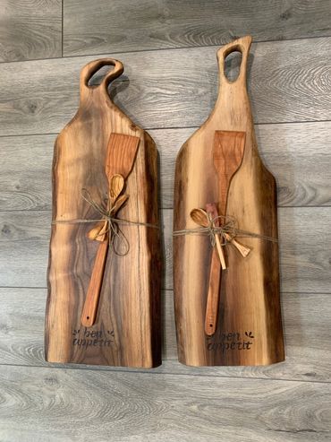 Two wooden cutting boards with wooden spatulas tied with twine, engraved 'bon appetit'.