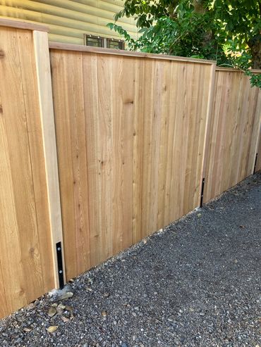 Solid style privacy fence with exposed posts and top cap board. 