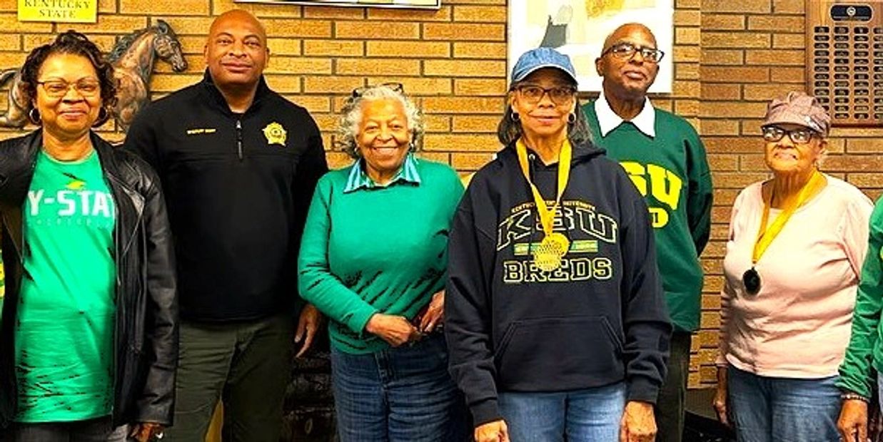 Group of people wearing Kentucky State University apparel and medals.