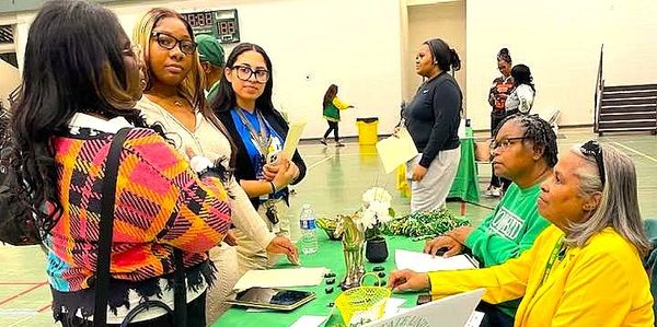 People engaged in a discussion at a community event table.