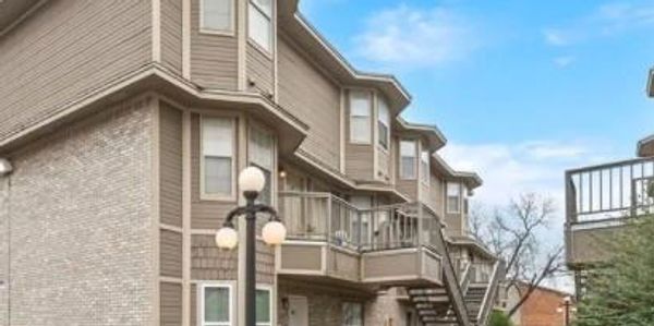 Modern townhouses with beige siding and balconies under a clear blue sky.