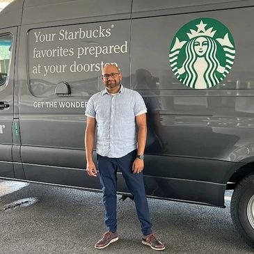 Man standing next to a Starbucks delivery van promoting doorstep service.