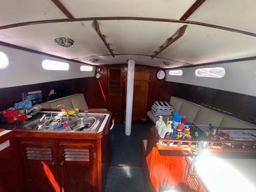 Interior of a cozy sailboat cabin with wooden furnishings and small windows.