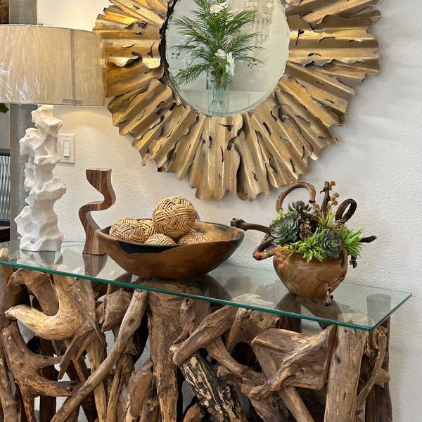 Decorative mirror above a driftwood console table with unique art pieces and plants.