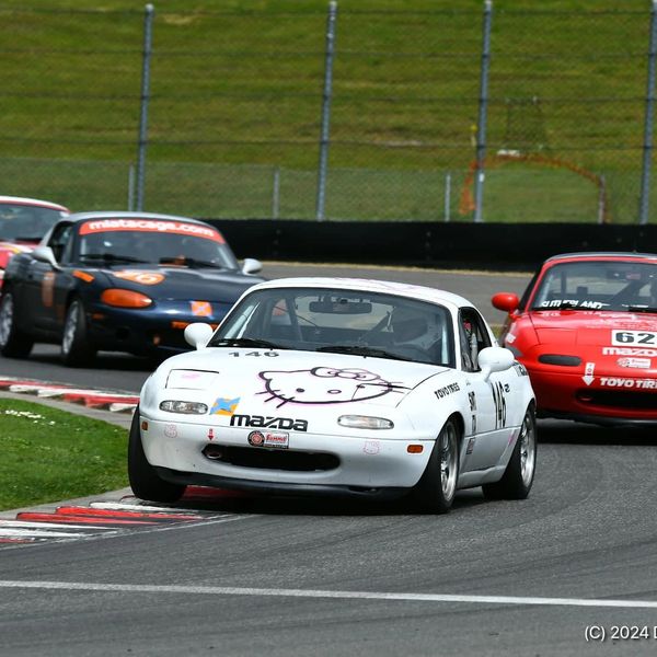 White Mazda race car with Hello Kitty decal on track.