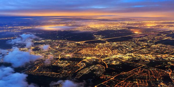 Aerial view of a city illuminated at dusk with a colorful sky.