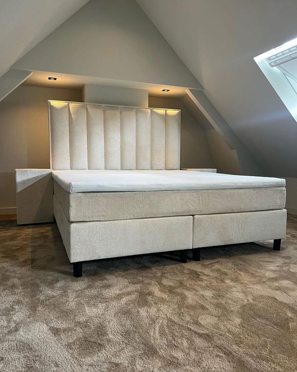 Modern beige upholstered bed with vertical padded headboard in attic room.
