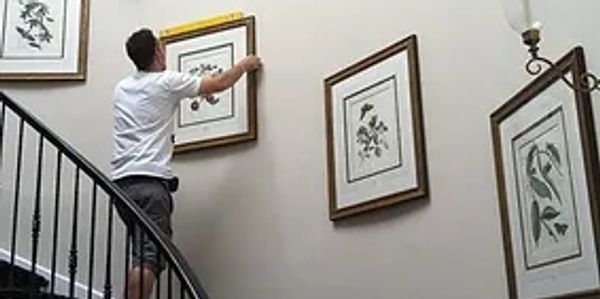 Man Installing Pictures on Spiral Staircase