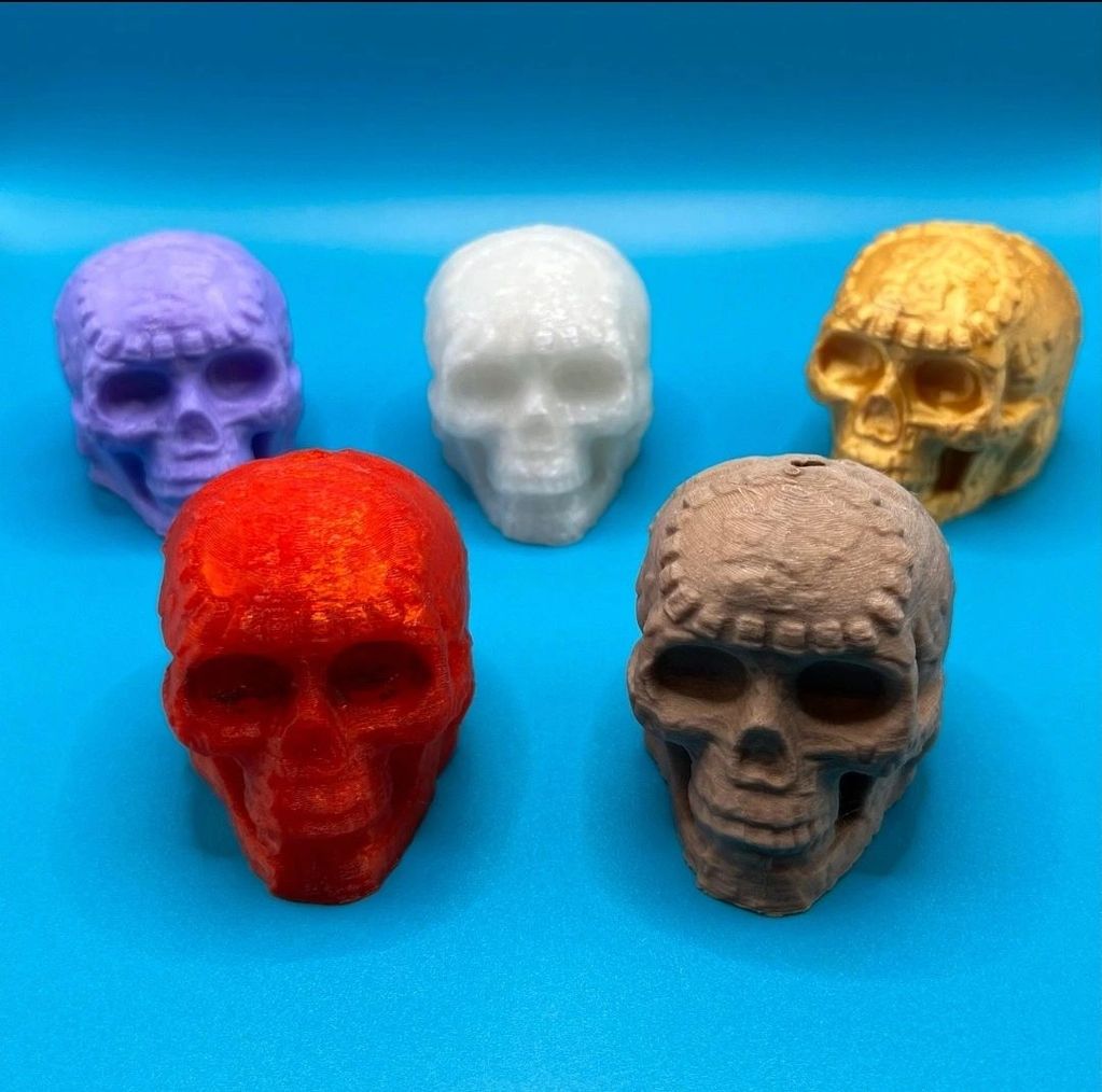 Five colorful 3D skulls on a blue surface.