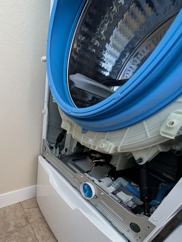 GE washing machine with front panel striped off. Drain pump repair
