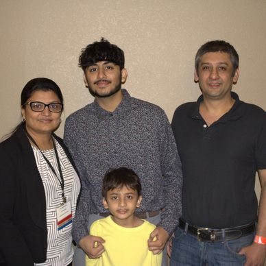 A family of four posing together indoors, smiling.