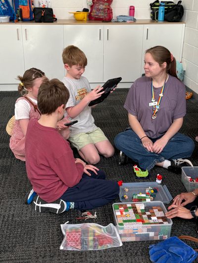 Three children and a teenager playing with magnetic blocks and looking at an iPad