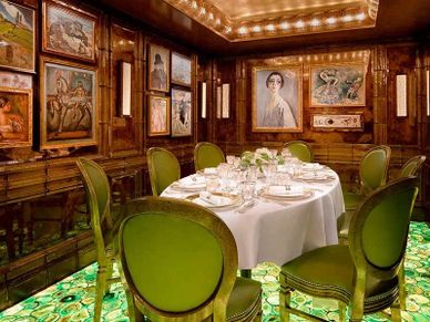Elegant dining room with green chairs and illuminated floor art.