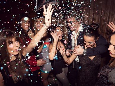 A lively group celebrating with confetti at a party.