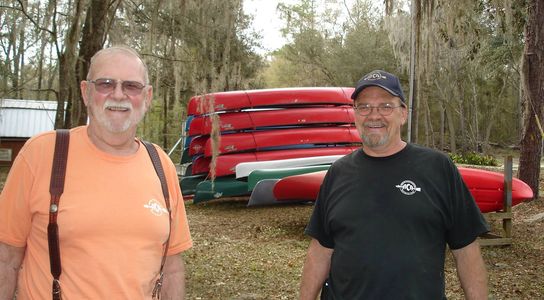 John and Wendell Hannum posing in front of a canoe rack.