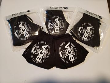 Black face masks with a white BCA logo, four packaged and two unpackaged.