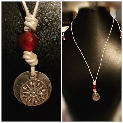 A metallic pendant with a red stone