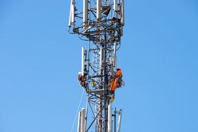 Worker in safety gear inspecting rooftop telecom equipment