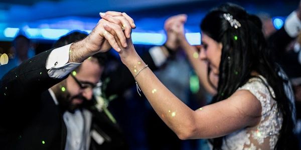 A couple holding hands and dancing at a wedding reception.