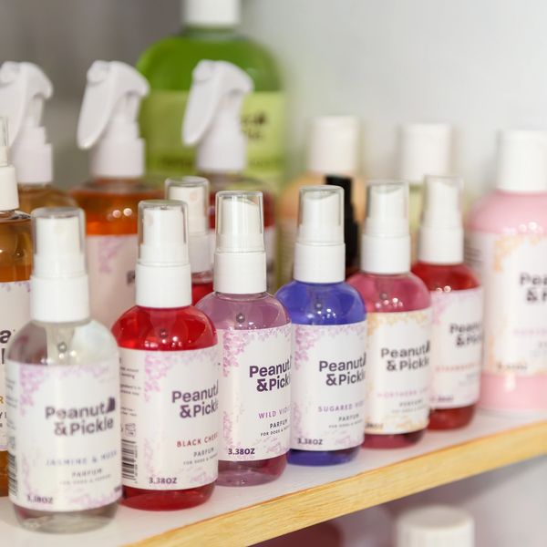 A shelf with various colorful Peanut & Pickle parfum bottles for pets. Holistic grooming