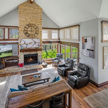 Cozy living room with stone fireplace and large windows.