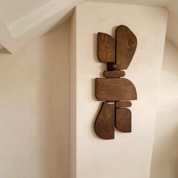 Abstract wooden wall art mounted on a light beige wall.