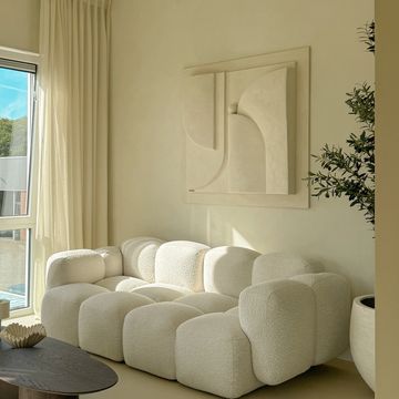 Modern cream modular sofa in a sunlit living room with abstract wall art.