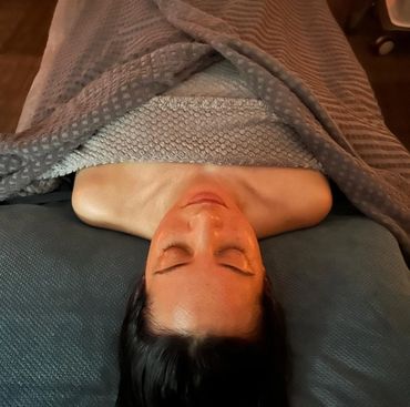 woman lay with eyes closed on massage table under towels