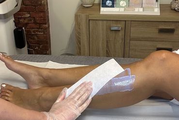 leg with wax and wax strip being held on it by hand in glove