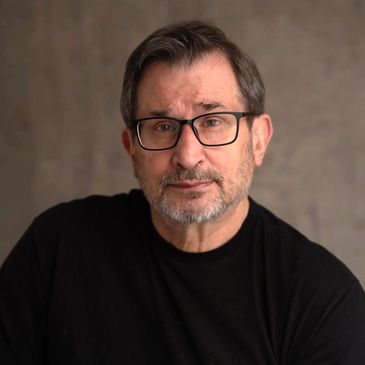 Middle-aged man with glasses and beard wearing a black shirt.