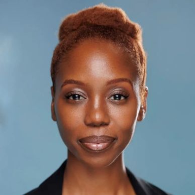 Confident woman with natural hair and a calm expression against a blue background.