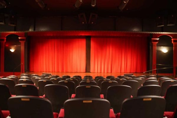 Empty theater with red curtains and rows of seats.