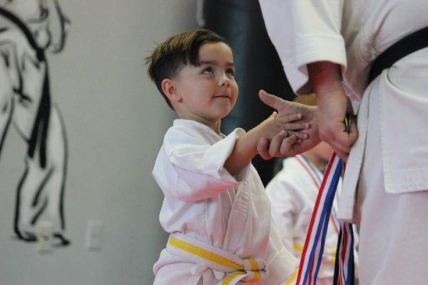 Young karate student in a white uniform receiving personal instruction from an instructor at West Coast Karate in Lutz, Florida.