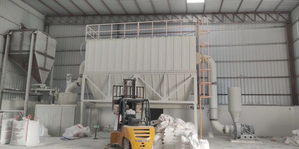 Industrial warehouse with machinery, jumbo bags, and a forklift.