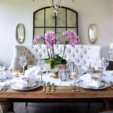 Elegant dining table set with white plates and pink orchids centerpiece.