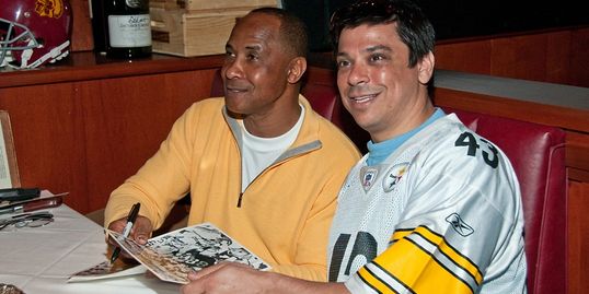 NFL Hall of Fame Lynn Swann signing autographs for guest at past Super Bowl party