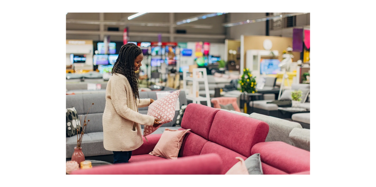 Black girl checking out a pink pillow in a furniture showroom