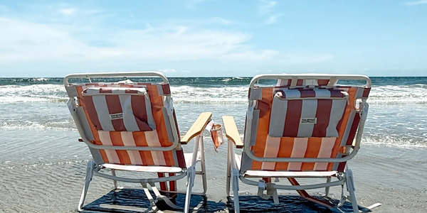 Two striped beach chairs face the ocean on a sunny day.