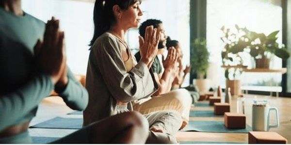 People meditating in a peaceful yoga studio with natural light.