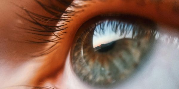 Close-up of an eye reflecting a scenic sunset.